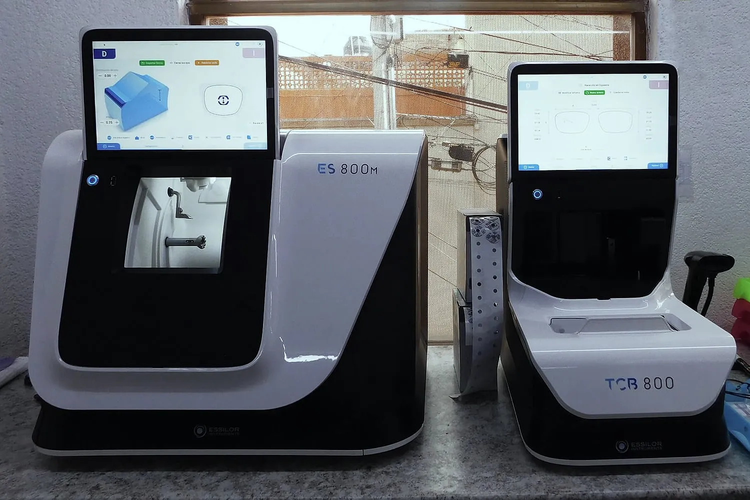 Dos equipos Essilor, un ES 800M y un TCB 800, con sus pantallas encendidas sobre una mesa de trabajo