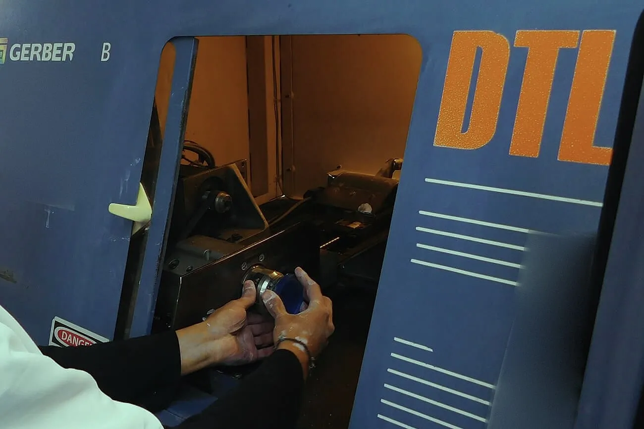 Manos colocando una lente en la máquina de tallado Gerber DTL, vista de cerca